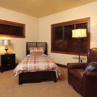 A cozy bedroom with a single bed, armchair, and warm lighting.