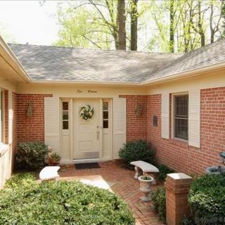 A charming brick house entrance with a welcoming garden path and greenery.