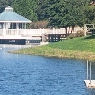 A serene view of a gazebo by the water, surrounded by lush greenery.