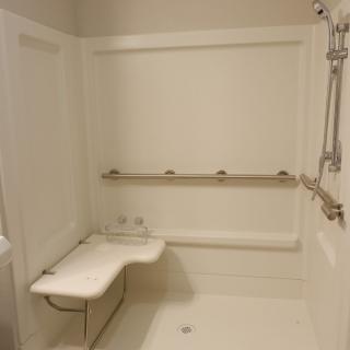 An accessible shower with grab bars and a folding seat for safety.