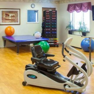 A fitness room featuring an exercise bike, therapy balls, and a rack of weights.