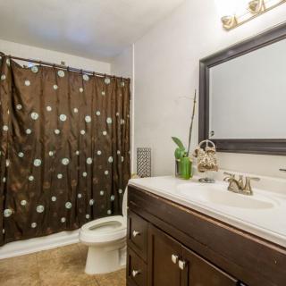 A well-lit bathroom with a brown polka dot shower curtain and dark wood vanity.