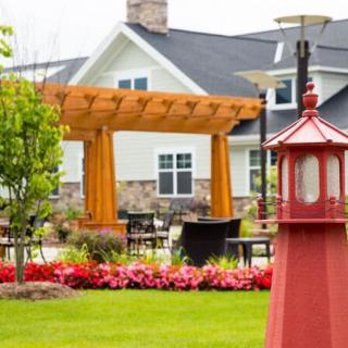 A beautifully landscaped garden featuring a pergola, colorful flowers, and outdoor seating in front of a charming house.
