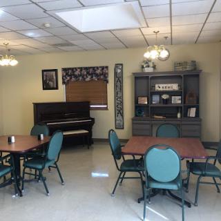 A cozy dining area featuring tables, chairs, and a piano, designed for community gatherings.