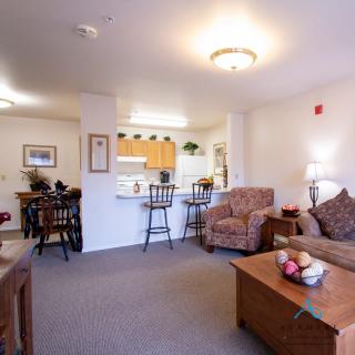 A cozy open-layout living space featuring a living room and adjacent kitchen with warm lighting.