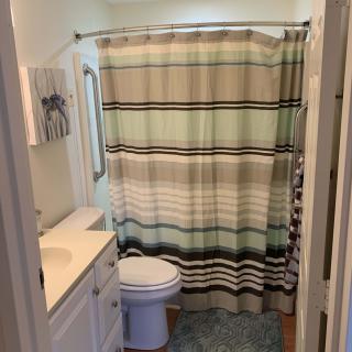 A small bathroom featuring a striped shower curtain, sink, and toilet.