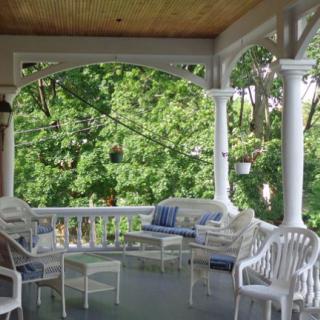 A cozy porch with outdoor seating surrounded by lush greenery.