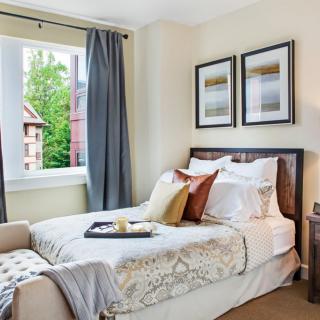 Cozy bedroom with single bed and stylish decor, featuring framed artwork and a window view.