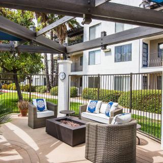 A cozy outdoor patio area with seating and a fire pit in an apartment complex.