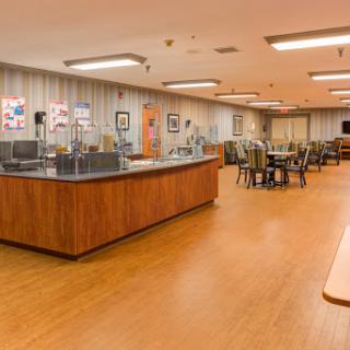 A spacious cafeteria with wooden flooring and seating arrangements.