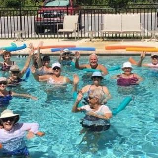 A group of people enjoying a fun day in the pool with water noodles.
