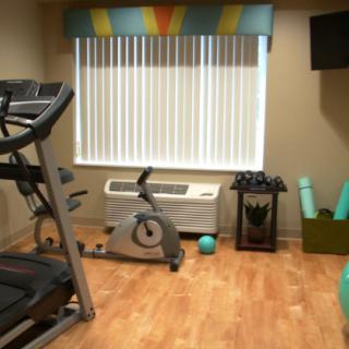 A small home gym with fitness equipment including a treadmill, exercise bike, and yoga mats.