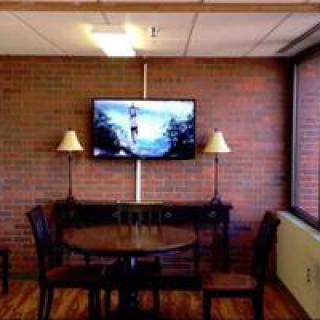 A cozy room interior featuring a brick wall, a mounted television, and a small table with chairs.