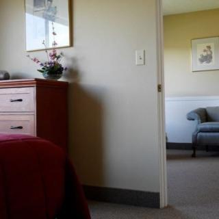 A view from a bedroom into a living room, featuring a dresser and an open doorway.