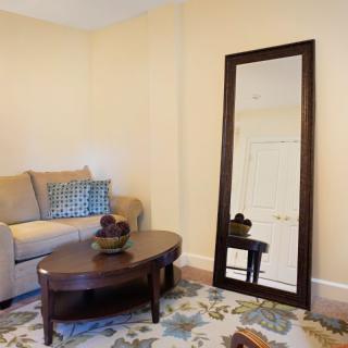 A cozy living room with a large floor mirror, comfortable sofa, and decorative coffee table.