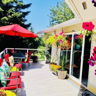 A sunny patio with vibrant flowers and comfortable seating under a red umbrella.
