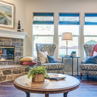 A cozy living room with elegant seating, a stone fireplace, and decorative accents.