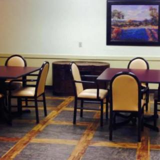 A dining area with tables, chairs, and a painting on the wall.