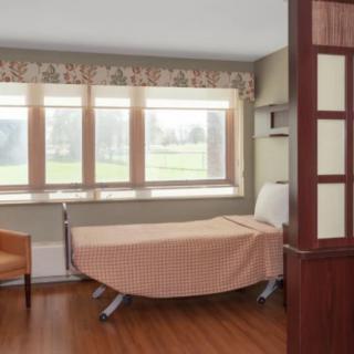 A bright hospital room with a bed and large windows letting in natural light.