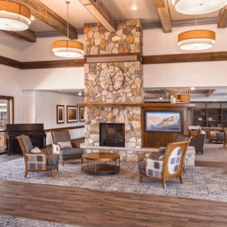 A cozy hotel lobby with a stone fireplace, surrounded by comfortable seating and wooden accents.