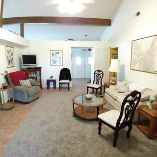 A cozy living room with a mix of classic and modern furniture, featuring a sofa, chairs, coffee table, and television.
