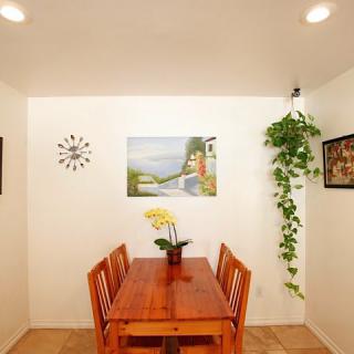 A cozy dining room with a wooden table, chairs, wall art, and decorative plants.