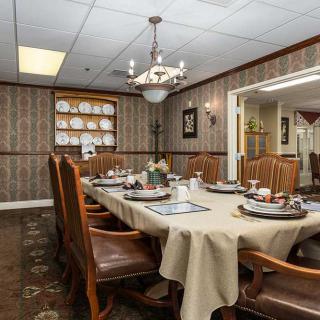 A well-decorated dining room with a large table set for a meal, featuring elegant chairs and a chandelier.