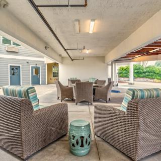 A cozy outdoor patio with rattan chairs and a decorative stool under a covered area.