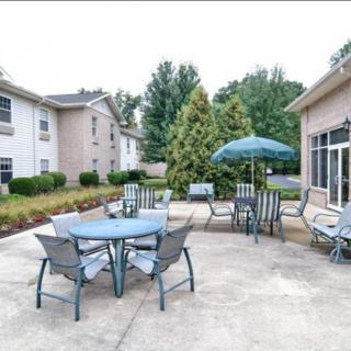 An outdoor patio area with tables, chairs, and an umbrella near a building.