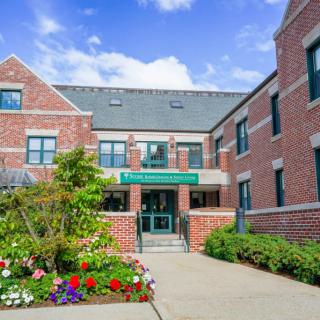 A brick building entrance with a garden and pathway.
