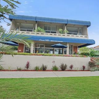 A two-story building with blue awnings, surrounded by landscaped grass and plants.