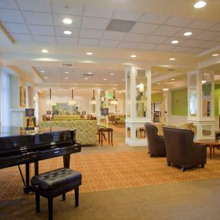 A spacious lounge area featuring a grand piano, comfortable seating, and ambient lighting.