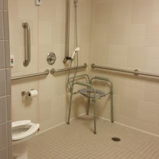 An accessible bathroom featuring a shower, grab bars, and a shower chair for individuals with mobility challenges.