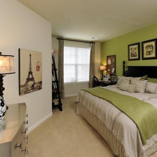 A cozy bedroom with a green accent wall, elegant decor, and a comfortable bed.