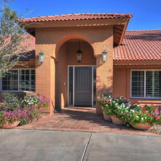 A welcoming entrance of a residential house with a well-kept garden and floral decorations.