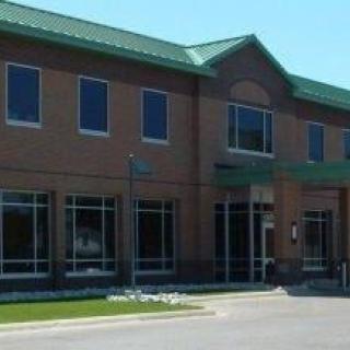 A two-story brick commercial building with large windows and a green roof.