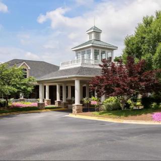 A scenic view of a building entrance surrounded by trees and landscaping.
