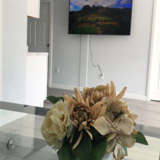 A modern living room with a decorative flower arrangement on the table and a wall-mounted TV.