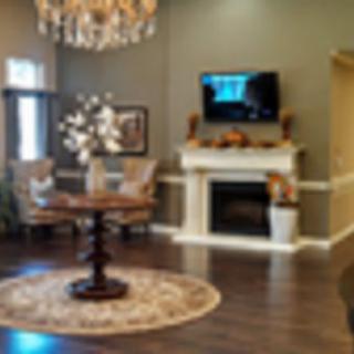 An elegantly decorated living room with a chandelier, fireplace, and television.