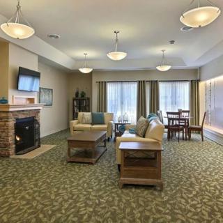 Spacious living room with modern furnishings, featuring a sofa, table, fireplace, and a wall-mounted television.