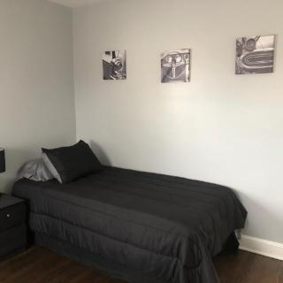 A minimalist bedroom with a single bed, gray bedding, and wall art.