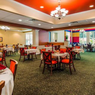 An elegantly designed restaurant dining area with neatly arranged tables and chairs, showcasing warm lighting and a carpeted floor.