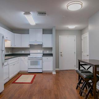 A modern kitchen with white cabinets and a small dining area.