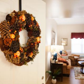 A cozy living room is adorned with an autumn-themed wreath on the door.