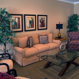 A cozy living room with a beige sofa, glass coffee table, and framed wall art.