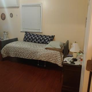A cozy bedroom with a neatly made bed, nightstand, and lamp.