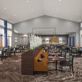 A modern restaurant dining area with neatly arranged tables and chairs, featuring decorative lighting and carpeted flooring.
