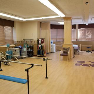 A spacious rehabilitation center equipped with various physical therapy equipment and exercise tools.
