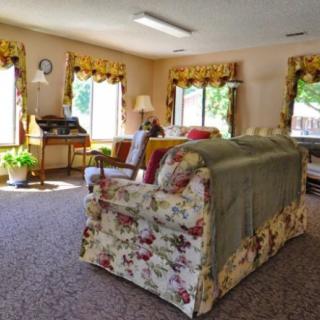 A cozy living room with floral-patterned sofas and large windows allowing natural light to fill the space.