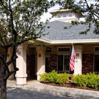 A view of a house with an American flag and surrounding trees.